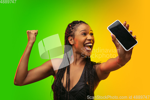 Image of Portrait of young woman in neon light on gradient backgound. The human emotions, black friday, cyber monday, purchases, sales, finance concept.