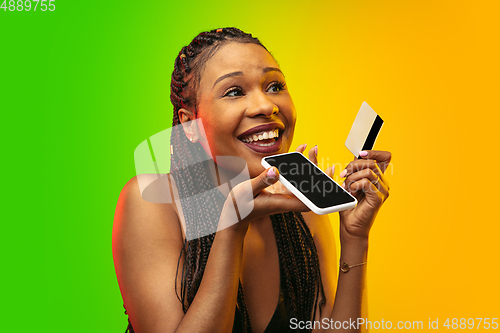 Image of Portrait of young woman in neon light on gradient backgound. The human emotions, black friday, cyber monday, purchases, sales, finance concept.