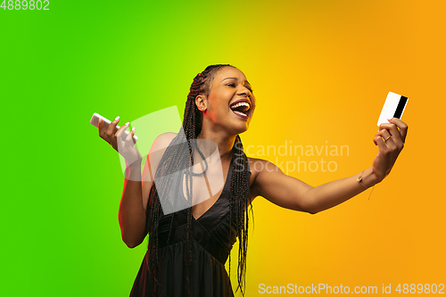 Image of Portrait of young woman in neon light on gradient backgound. The human emotions, black friday, cyber monday, purchases, sales, finance concept.