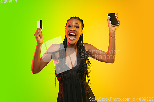 Image of Portrait of young woman in neon light on gradient backgound. The human emotions, black friday, cyber monday, purchases, sales, finance concept.