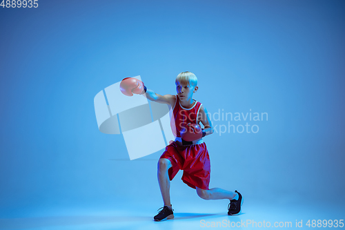 Image of Teenager in sportswear boxing isolated on blue studio background in neon light