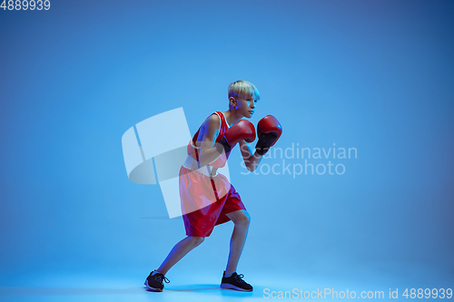 Image of Teenager in sportswear boxing isolated on blue studio background in neon light