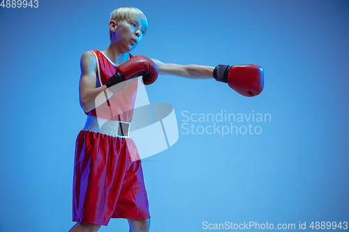 Image of Teenager in sportswear boxing isolated on blue studio background in neon light