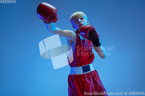 Image of Teenager in sportswear boxing isolated on blue studio background in neon light