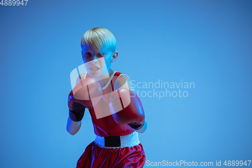 Image of Teenager in sportswear boxing isolated on blue studio background in neon light