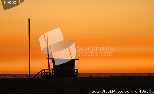 Image of A lifeguard shack on a beach against a golden sunset
