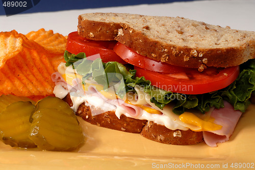 Image of Ham, cheese, lettuce and tomato sandwich with pickles and chips