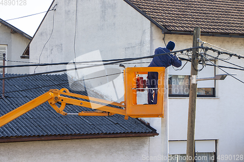 Image of Electrician worker on a pole, repairing power lines