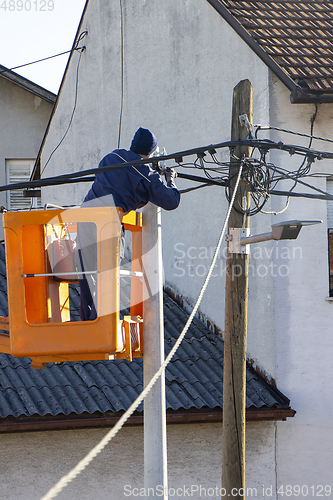 Image of Electrician worker on a pole, repairing power lines