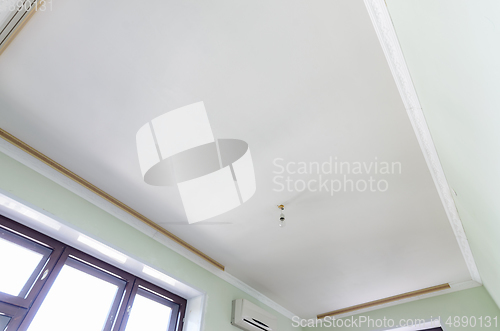 Image of Plastered white ceiling in the room, a temporary light bulb hangs on the ceiling