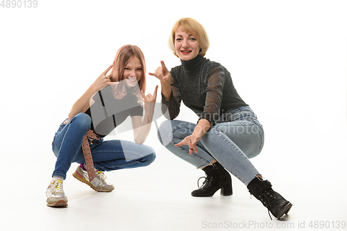 Image of Mother and daughter teenager knelt down and cheerfully show youth gestures in the frame