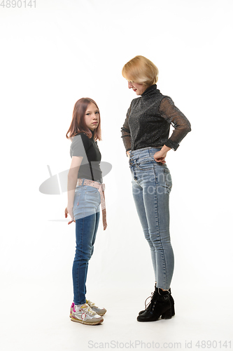 Image of The mother reproachfully looks at the guilty daughter, the daughter looks sadly into the frame, isolated on a white background