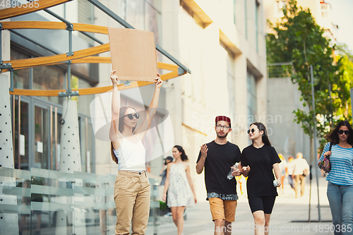 Image of Dude with sign - woman stands protesting things that annoy her