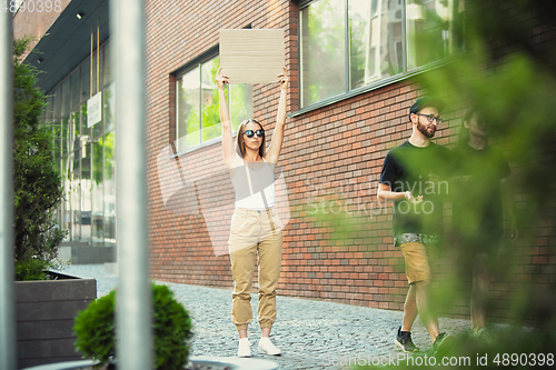 Image of Dude with sign - woman stands protesting things that annoy her