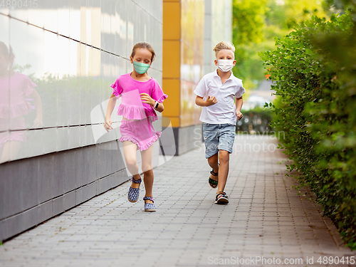 Image of Happy little caucasian kids jumping and running on the city street