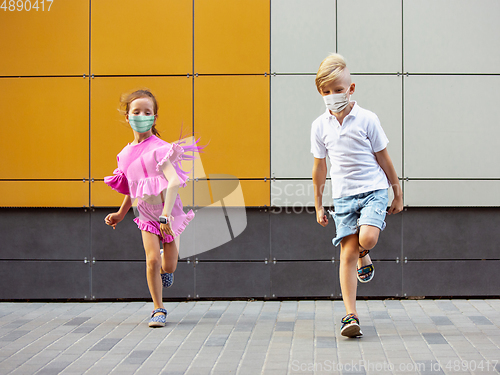 Image of Happy little caucasian kids jumping and running on the city street