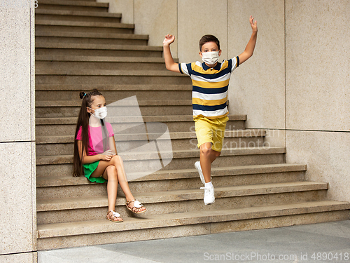 Image of Happy little caucasian kids jumping and running on the city street