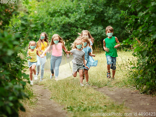 Image of Happy little caucasian kids jumping and running on the meadow, in forest