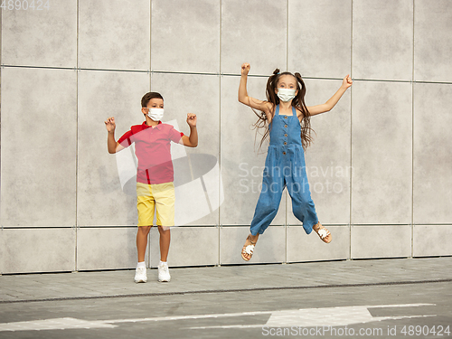 Image of Happy little caucasian kids jumping and running on the city street