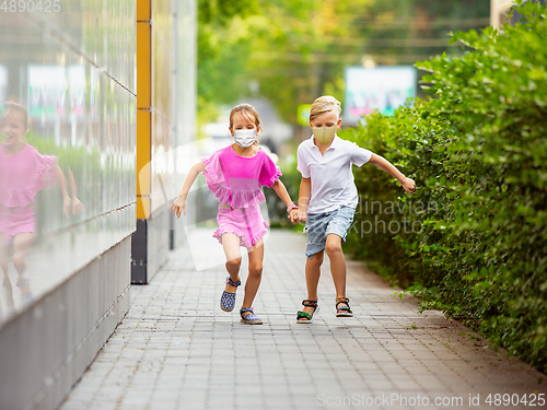 Image of Happy little caucasian kids jumping and running on the city street