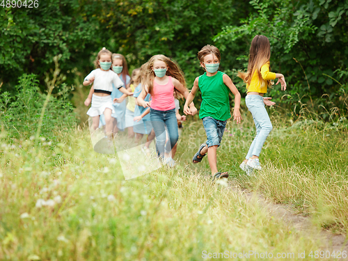 Image of Happy little caucasian kids jumping and running on the meadow, in forest