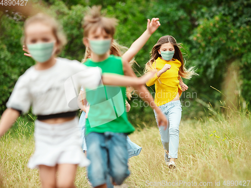 Image of Happy little caucasian kids jumping and running on the meadow, in forest