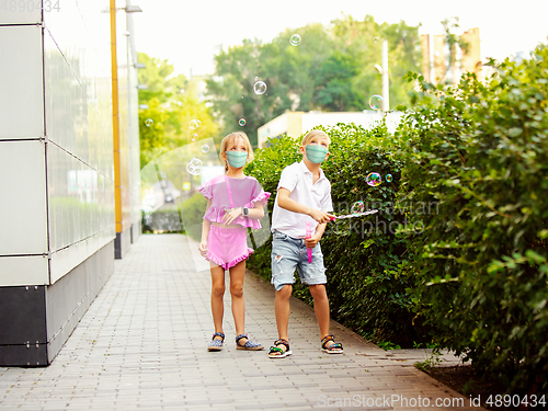 Image of Happy little caucasian kids jumping and running on the city street