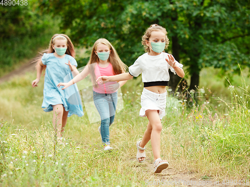 Image of Happy little caucasian kids jumping and running on the meadow, in forest