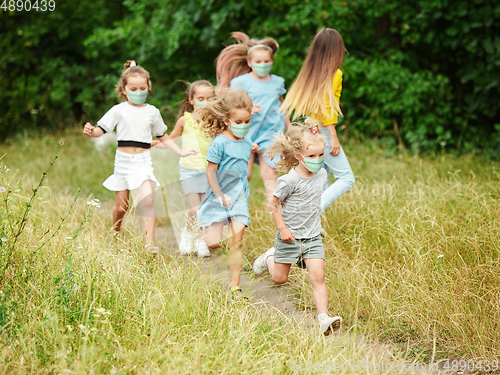 Image of Happy little caucasian kids jumping and running on the meadow, in forest