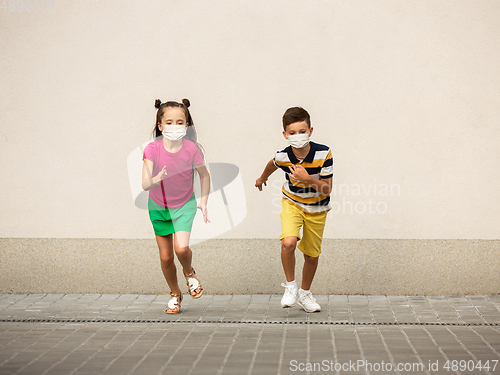 Image of Happy little caucasian kids jumping and running on the city street