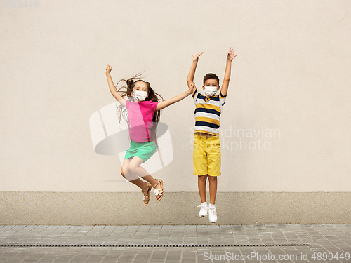 Image of Happy little caucasian kids jumping and running on the city street