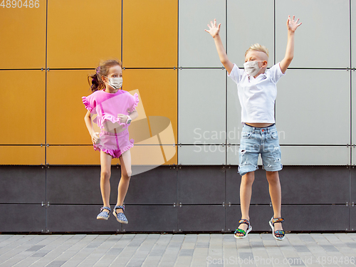 Image of Happy little caucasian kids jumping and running on the city street