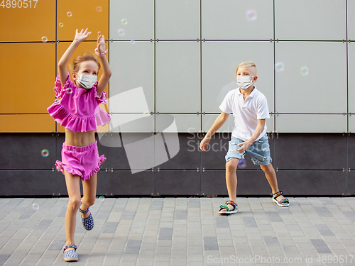 Image of Happy little caucasian kids jumping and running on the city street