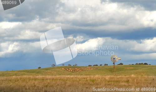 Image of Windmill on a California hillside under a cloud filled sky