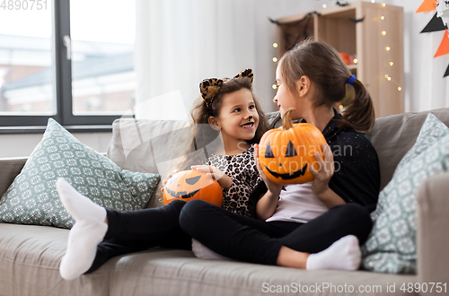 Image of girls in halloween costumes with pumpkins at home