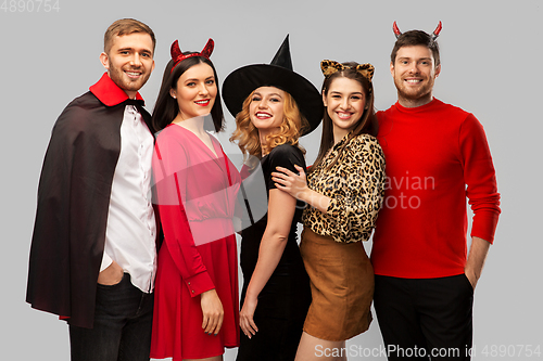 Image of happy friends in halloween costumes over grey