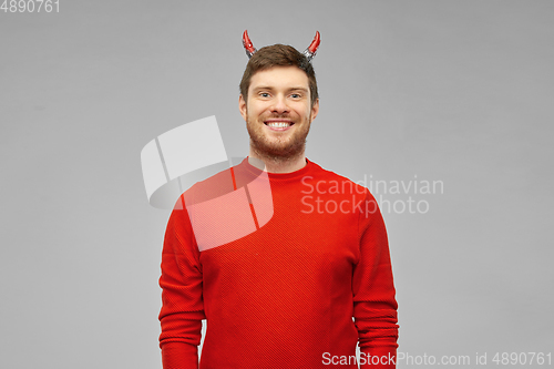 Image of happy man in halloween costume of devil over grey