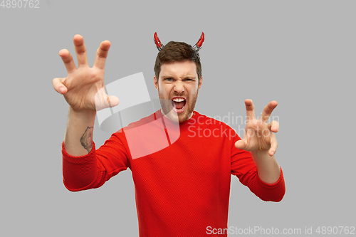 Image of man in halloween costume of devil scaring