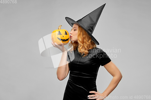 Image of woman in halloween costume of witch kisses pumpkin