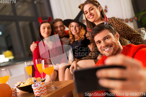 Image of happy friends in halloween costumes taking selfie