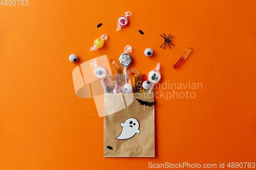 Image of halloween sweets in paper bag on orange background