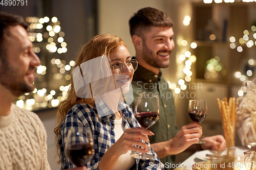 Image of happy friends drinking red wine at christmas party