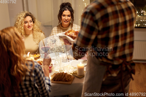 Image of happy friends having christmas dinner at home