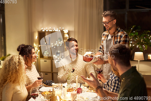 Image of happy friends having christmas dinner at home