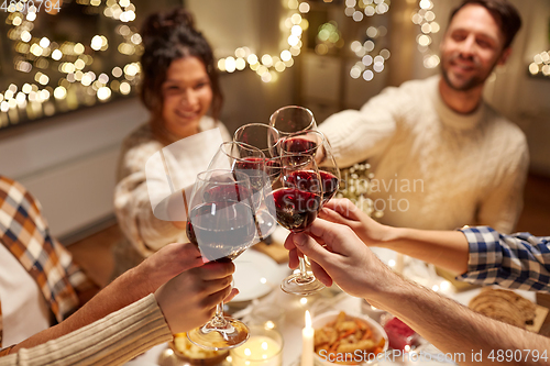 Image of happy friends drinking red wine at christmas party