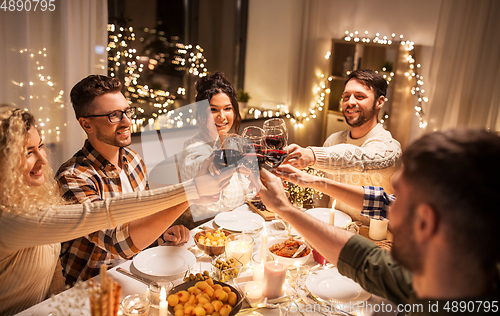 Image of happy friends drinking red wine at christmas party