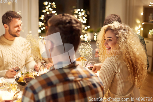 Image of happy friends having christmas dinner at home