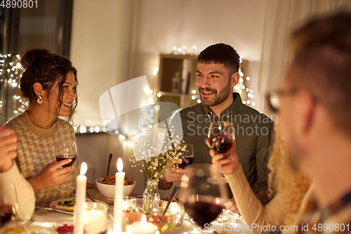 Image of happy friends drinking red wine at christmas party