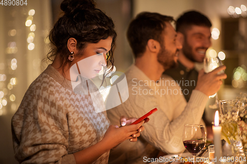 Image of woman with smartphone at dinner party with friends