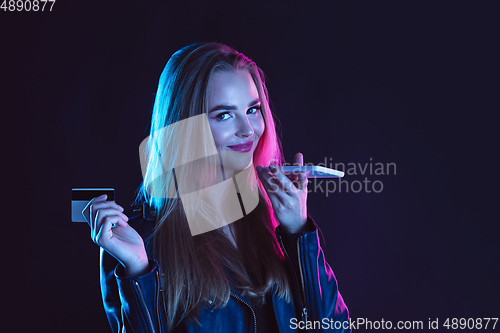 Image of Portrait of young woman in neon light on dark backgound. The human emotions, black friday, cyber monday, purchases, sales, finance concept.